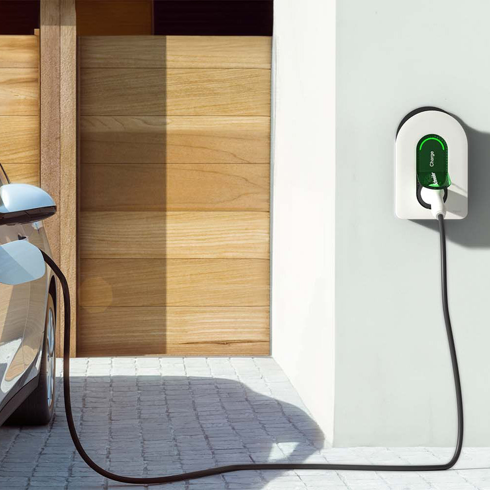 Φορτιστής τοίχου Schneider Electric Schneider Charge σε λειτουργία, συνδεδεμένος με ηλεκτρικό όχημα σε οικιακό χώρο στάθμευσης.
