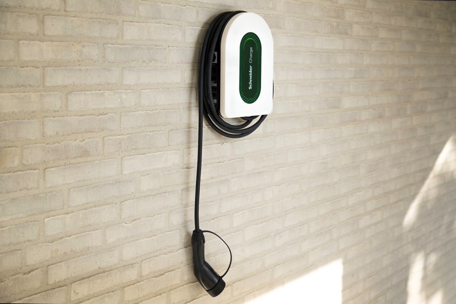 Φορτιστής τοίχου Schneider Electric Schneider Charge με ενσωματωμένο καλώδιο Type 2 εγκατεστημένος σε τοίχο, έτοιμος για φόρτιση ηλεκτρικού οχήματος.