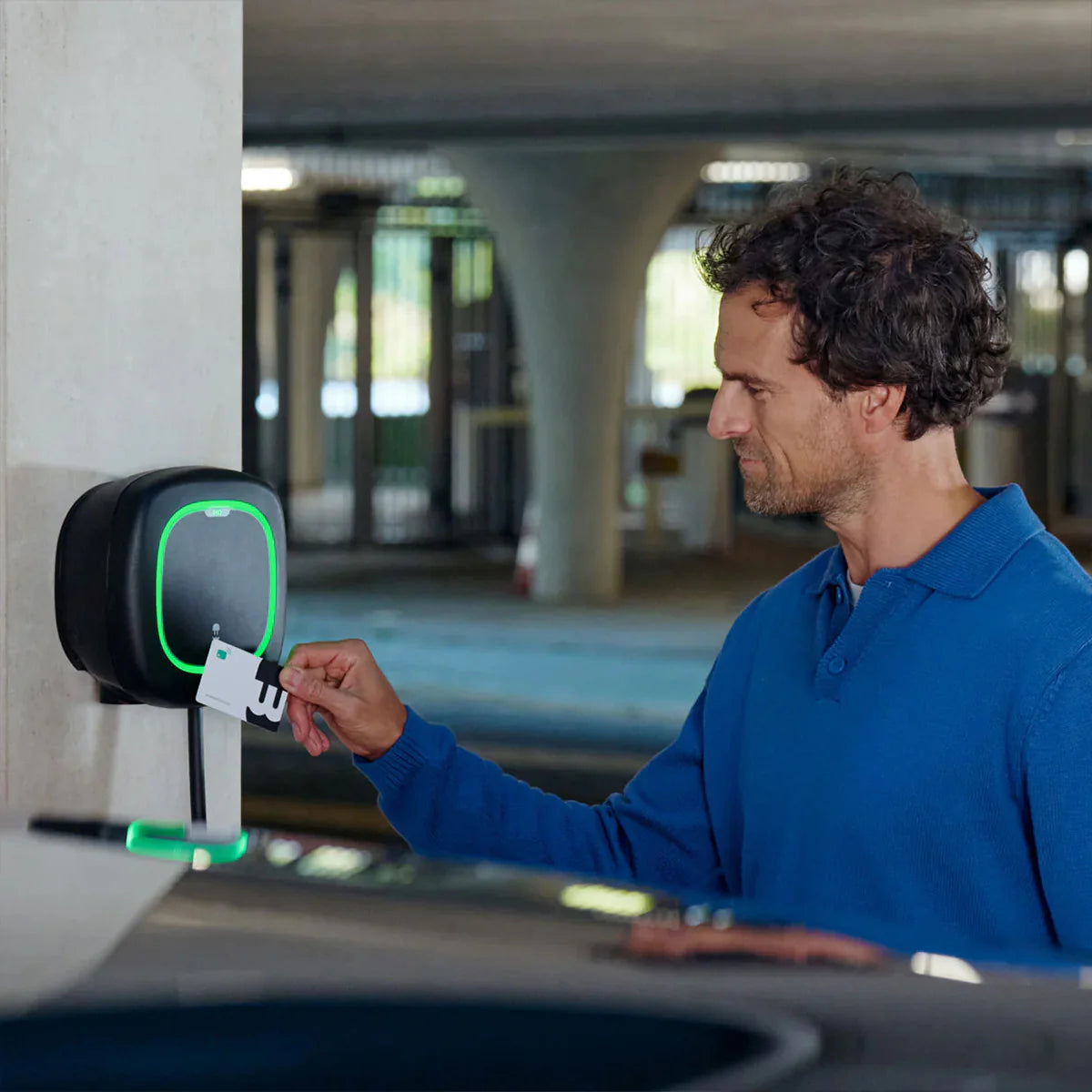 Άνδρας φορτίζει με κάρτα RFID σε επιτοίχιο φορτιστή Wallbox Pulsar Pro με ενσωματωμένο καλώδιο Type 2.